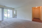 Located at 3100 Hampton Hwy in Yorktown, Virginia, this single-floor residence offers a practical and comfortable layout suited for everyday living. The kitchen is well-equipped with warm oak cabinetry providing generous storage, light countertops, a gas range, an under-cabinet ventilation hood, and hardwood-style flooring that adds a clean, grounded feel to the space. A sliding glass door in the living area fills the room with natural light and offers a view of the outdoors, creating an open and airy atmosphere. The bedrooms are carpeted throughout, maintaining a soft, quiet environment. One bedroom features dual closets with bifold doors, offering exceptional storage capacity, while additional bedrooms include their own closet space and windows that bring in natural light and outdoor views. A ceiling light fixture accents one of the bedrooms, adding a classic touch. The bathroom is finished with white subway tile surrounding a full soaking tub and shower combination, complemented by clean white tile flooring, keeping the space bright and easy to maintain. Overall, the unit presents a straightforward, functional design with consistent neutral tones, practical finishes, and a well-organized single-level floor plan.
