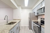 Located at 4102 Brickell Dr in Fairfax, VA, this well-appointed 2-bedroom, 2-bathroom residence offers a thoughtfully designed single-level layout. The open-concept living and dining area is anchored by a classic wood-burning fireplace and flows seamlessly toward a private balcony, with natural light streaming in through multiple windows.

The kitchen is a functional highlight, featuring granite countertops, gray cabinetry, a peninsula with a single-basin sink and gooseneck faucet, and a full suite of stainless steel appliances including a refrigerator, electric range, and built-in microwave. A skylight above adds additional brightness. Adjacent pantry and dining spaces provide practical storage and flexible use.

The spacious primary bedroom offers generous square footage with access to closet space, while the second bedroom is well-sized and similarly finished. Three closets throughout the unit, including a walk-in with wire shelving, ensure ample storage. Both bathrooms are finished with granite vanity tops and light-toned flooring. An in-unit laundry area adds everyday convenience.

Throughout the residence, light gray wood-style flooring ties the spaces together with a clean, modern aesthetic, complemented by crisp white walls and consistent neutral tones.
