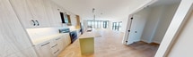 This contemporary apartment, located at 112 St James St in London, Ontario, offers 1580 square feet of thoughtfully designed living space. The open-concept floor plan seamlessly integrates the living room and kitchen, creating an expansive area ideal for both relaxation and entertaining. Large windows throughout flood the space with natural light and provide stunning city views.

The modern kitchen is a standout feature, boasting light wood cabinetry, a striking green island, and high-end stainless steel appliances. A stylish pendant light fixture adds a touch of elegance to the culinary space.

The apartment includes three bedrooms, with the primary bedroom measuring a generous 210 square feet. Two well-appointed bathrooms showcase modern design elements, including a walk-in shower with terrazzo-style flooring and sleek vanities with oval mirrors.

Additional amenities include a separate laundry room with stacked washer and dryer, and ample storage space. The apartment's neutral color palette and warm wood-look flooring create a harmonious and inviting atmosphere throughout. High ceilings and recessed lighting further enhance the sense of spaciousness and contemporary ambiance.