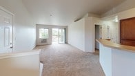 Located in Liberty Lake, Washington, this single-floor residence offers a well-designed open-concept layout that seamlessly connects the living, dining, and kitchen areas. The living room features vaulted ceilings, a ceiling fan, plush carpeting, and a sliding glass door that opens to a private balcony with outdoor views of the surrounding neighborhood. Natural light fills the space through multiple windows, enhancing the bright and airy atmosphere throughout.

The kitchen is equipped with warm-toned wood cabinetry, light countertops, and a full suite of black appliances including an electric range, dishwasher, and refrigerator. A peninsula counter with a breakfast bar connects the kitchen to the living area, providing a functional and social space. Track lighting above the kitchen adds focused illumination.

The bedroom is generously sized with soft carpeting, a large window with neighborhood views, and baseboard heating. A sizable walk-in closet with wire shelving offers ample storage.

The bathroom features tile flooring, a wood-cabinet vanity, and a full tub-shower combination. Conveniently adjacent is a dedicated laundry area with a full-size washer and dryer. This well-appointed residence provides comfortable, practical living in a welcoming community setting.