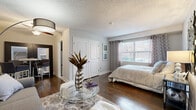 Located at 4440 Roanoke Pkwy in Kansas City's Roanoke neighborhood, this well-appointed 1-bedroom, 1-bathroom unit offers a thoughtfully designed single-floor layout. Rich hardwood flooring flows throughout the living room and bedroom, adding warmth and continuity to the space.

The living room is an inviting area highlighted by neutral gray tones, a ceiling fan, and ample room for comfortable seating arrangements. It opens naturally toward the kitchen and dining area, promoting an open, connected feel.

The kitchen features a galley-style configuration with dark cabinetry, stainless steel appliances including a full-size refrigerator and dishwasher, a tile backsplash, and a window that brings in natural light. Light tile flooring and bamboo window shades complete the clean, functional aesthetic.

The bedroom is a comfortable retreat with large windows dressed in patterned drapes that allow for abundant natural light and views of the surrounding greenery. A double-door closet provides practical storage, and the rich hardwood floors continue throughout.

The bathroom is finished in a crisp, all-white palette with tile surround in the tub/shower combo, light wood-look flooring, a granite-topped dark vanity, and a window for ventilation and natural light.

A connecting hallway ties the rooms together efficiently, making excellent use of the compact yet functional floor plan.