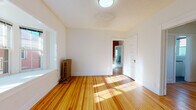 Located in Denver's vibrant Capitol Hill neighborhood, this single-floor unit at 1535 N Grant St blends historic character with thoughtful updates throughout. Warm, honey-toned hardwood floors run through the living areas, complemented by crisp white walls and an abundance of natural light streaming through multiple windows. Classic cast-iron radiators add a charming period detail to several rooms, reinforcing the home's historic roots.

A standout feature is the room with a dramatic exposed brick accent wall, adding texture and industrial character to the space. A ceiling fan and direct access to the adjacent sun-filled room make this a versatile and inviting area. The living room is anchored by a wide bay window that frames neighborhood views and fills the space with light.

The kitchen has been well-appointed with white shaker cabinetry, dark slate countertops, a white subway tile backsplash, a stainless steel sink, and a gas range, all set atop dark slate floor tiles — a clean, functional contrast to the warm tones found throughout the rest of the unit.

The bathroom retains its vintage charm with a classic clawfoot soaking tub, white hexagonal tile flooring, full subway tile walls, a pedestal-style vanity, and a window that provides natural ventilation and light. The entry area features original millwork and gold-toned hardware, completing this characterful Denver home.