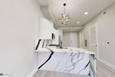 Located at 187 Culver Avenue in Jersey City, NJ, this thoughtfully designed one-bedroom, one-bathroom residence showcases modern finishes and a clean, contemporary aesthetic throughout. Light wood-style flooring runs seamlessly across the entire floor plan, lending a bright and cohesive feel to the space.

The kitchen serves as the centerpiece of the home, featuring striking floor-to-ceiling white gloss cabinetry, a dramatic Calacatta-style marble backsplash and peninsula with bold veining, and a full suite of stainless steel appliances including a gas range, over-the-range microwave, dishwasher, and a smart French door refrigerator. A geometric gold pendant light adds a refined accent above the peninsula.

The bedroom is a calm, light-filled room with black-framed windows that invite natural light and offer neighborhood views. A dedicated closet provides organized storage with built-in shelving and hanging rods, maximizing functionality.

The bathroom is a standout space, clad entirely in large-format Calacatta marble-style tile from floor to ceiling. A floating white vanity with silver hardware, a matte black faucet, and coordinating black accessories complete the polished, spa-inspired aesthetic.

Recessed lighting throughout and a neutral gray-white color palette give the entire residence a fresh, move-in-ready appeal.