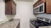 Located at 360 Broad Meadows Blvd in Columbus, Ohio, this single-floor residence offers a well-designed layout that balances comfort and functionality. The open living area is highlighted by warm hardwood-style flooring, clean white walls, and a ceiling fan with integrated lighting. A pass-through window connects the living space directly to the kitchen, enhancing the sense of openness and flow between the two areas.

The kitchen is efficiently arranged in a galley style, featuring rich dark wood cabinetry, granite countertops with subtle veining, white subway tile backsplash, and stainless steel appliances including an electric range and over-the-range microwave. Light tile flooring grounds the space with a clean, practical finish.

The bedrooms continue the hardwood-style flooring and are characterized by neutral tones, textured ceilings, and windows fitted with blinds that allow for natural light while maintaining privacy. Each bedroom offers views of surrounding greenery, contributing to a calm and pleasant atmosphere.

The bathroom is finished with tile flooring, a dark wood vanity with a white countertop, a large mirror, and a full tub-shower combination with tile surround. The overall design of the space is cohesive, featuring consistent finishes and a neutral palette that creates a clean, move-in-ready environment.