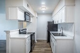 This single-story, two-bedroom, two-bathroom unit in Memphis, Tennessee, offers a straightforward and functional layout finished with consistent, modern details throughout. Light wood-look flooring runs through the living areas, bedrooms, and hallways, creating a cohesive and easy-to-maintain interior. Neutral white walls and textured ceilings contribute to a clean, bright aesthetic across the space.

Both bedrooms are comfortably sized, each featuring natural light from windows with blinds and ceiling fans with integrated lighting for added comfort and air circulation. One bedroom includes access to a walk-in closet, providing practical storage. The two bathrooms are finished with white cabinetry, marble-style countertops, framed mirrors, chrome fixtures, and wood-look flooring, maintaining a tidy and contemporary look.

The galley-style kitchen is efficiently arranged with white shaker cabinets, marble-look countertops, a stainless steel sink, and a full suite of appliances including an electric range, over-the-range microwave, dishwasher, and refrigerator. The overall layout, as seen in the 3D floorplan, connects rooms through a central hallway, supporting a practical and comfortable flow throughout the single-floor residence.