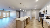 Located at 2620 W Sunshine St in Springfield, MO, this well-appointed 3-bedroom, 3-bathroom single-floor home offers a thoughtfully designed layout with modern finishes throughout. The open-concept kitchen and living area serves as the heart of the home, anchored by a large center island with a white quartz countertop, undermount sink, and elegant pendant lighting. White cabinetry with a subway tile backsplash, stainless steel appliances, and warm wood-look flooring complete the kitchen's clean, contemporary aesthetic. The living area extends naturally from the kitchen and opens through French doors onto a spacious outdoor deck, offering open views of the surrounding area. Each bedroom features plush carpet flooring, ceiling fans, and generous closet space with wire shelving systems. The well-sized primary bedroom connects to a private bathroom with a wide vanity, quartz countertop, and wood-look tile flooring. All three bathrooms maintain a consistent, modern design palette of soft grays and whites. A dedicated laundry room houses a full-size GE front-load washer and dryer. Additional highlights include a pantry, utility room, and five closets providing abundant storage throughout the home.