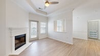 Located at 12100 W 136th St in Overland Park, Kansas, this single-story home offers a thoughtfully designed layout with a bright, neutral palette throughout. The living room serves as a focal point of the home, showcasing a tray ceiling with crown molding, a ceiling fan, and a classic white fireplace. Large windows with blinds allow generous natural light to fill the space, while a door provides direct access to an outdoor balcony or patio area. Light wood-look flooring extends throughout the main living areas, contributing to a clean, cohesive aesthetic.

The kitchen is well-appointed with white upper cabinetry, gray lower cabinets, white quartz countertops, a gray subway tile backsplash, and a full suite of stainless steel appliances. A peninsula with pendant lighting connects the kitchen to the open dining and living areas, enhancing the home's open-concept flow.

Bedrooms feature plush carpeting and ceiling fans, with at least one room offering a walk-in closet with built-in shelving. The bathroom includes a tiled tub-shower combination, a white vanity with quartz countertop, and wood-look flooring. A dedicated laundry area with an included washer and overhead wire shelving adds everyday convenience.