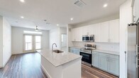Located at 375 Greenbriar Rd in Fate, TX, this well-appointed 2-bedroom, 2-bathroom single-story home offers a thoughtfully designed layout with modern finishes throughout. The open-concept kitchen serves as the centerpiece of the living area, showcasing a large granite-topped island with an undermount sink, two-tone cabinetry featuring white upper cabinets and sage-green lower cabinets, white subway tile backsplash, and a full suite of stainless steel appliances including a refrigerator with ice maker, electric range, microwave, and dishwasher. Rich wood-look flooring flows through the main living and kitchen areas, adding warmth and continuity. An in-unit laundry area is conveniently accessible from the kitchen. Both bathrooms are finished with granite-top vanities, sage cabinetry, and wood-look flooring, with one featuring a tiled tub/shower combo and the other a walk-in shower. Each bathroom provides direct access to a dedicated closet. The bedrooms are carpeted for comfort, each fitted with a ceiling fan and windows offering natural light and open outdoor views. The space combines clean, contemporary aesthetics with functional design, making it an attractive and practical home.