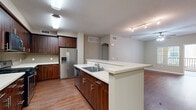 Located at 1510 Santa Diana Rd in Chula Vista, CA, this single-floor residence offers a well-designed layout with modern finishes throughout. The kitchen serves as a central highlight, showcasing rich dark wood cabinetry, light quartz countertops, a large island with an integrated sink, stainless steel appliances including a French door refrigerator with ice and water dispenser, a gas range, and a built-in microwave. A mosaic tile backsplash adds a refined touch, while hardwood-style flooring runs seamlessly through the main living areas. The living space is bright and open, featuring a ceiling fan with lighting, a window with exterior views, and direct access to a private balcony through an arched doorway. The primary bathroom is appointed with a dual-sink vanity, dark wood cabinetry with quartz countertops, a large walk-in glass shower, and well-lit mirrors. The bedrooms feature plush carpeting and generous walk-in closets equipped with wire shelving systems, providing ample storage. Neutral warm tones and clean white trim are consistent throughout, contributing to the space's calm and contemporary ambiance. A mini-split climate system is also present for efficient temperature control.