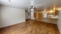 Located at 7806 SW Blue Jay Ln in Bentonville, Arkansas, this single-story 2-bedroom, 2-bathroom home offers a practical and comfortable layout across its well-utilized floor plan. The living room greets you at the entry with rich wood-look laminate flooring, neutral painted walls, a ceiling fan with light fixture, and a window that allows natural light to fill the space. It flows seamlessly into the kitchen and dining area, creating an open and connected common space. The kitchen is well-appointed with warm honey-toned wood cabinetry, ample counter space, a peninsula breakfast bar, tile flooring, and white appliances including a range, dishwasher, and refrigerator. Both bedrooms are carpeted and feature ceiling fans, windows for natural light, and generous closet storage. The primary bedroom includes a double-door closet, while the second bedroom also benefits from closet space and a direct connection to the kitchen area. Each of the two full bathrooms is equipped with a tub/shower combination featuring clean white surrounds and tile flooring, offering functionality and ease of maintenance. The home's straightforward single-floor layout makes for easy navigation throughout, presenting a move-in ready option in a well-established Bentonville neighborhood.