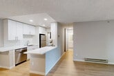 Located at 2850 Middlefield Rd in Palo Alto, CA, this two-bedroom, one-bathroom residence offers a thoughtfully designed single-floor layout. Light wood-style flooring runs throughout, complemented by neutral gray walls and textured ceilings that lend a clean, contemporary feel.

The kitchen is a standout feature, designed in a galley style with crisp white cabinetry, white subway tile backsplash, quartz countertops, and a full suite of stainless steel appliances including a refrigerator, range, microwave, and dishwasher. A peninsula counter opens toward the living area, creating a natural connection between the kitchen and living room. The living room is bright, with multiple windows that bring in natural light and views of surrounding greenery, plus a sliding glass door leading to a private balcony.

The primary bedroom is a comfortable size, featuring a window with outdoor views and a baseboard heating unit. The second bedroom offers similar simplicity with wood flooring and good natural light. The bathroom is well-appointed with white cabinetry, quartz countertops, a large vanity mirror, and a tiled tub-shower combination. A dedicated laundry area houses a stacked GE washer and dryer unit. The hallway connects all rooms efficiently, completing this functional and modern Palo Alto residence.