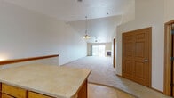 This single-floor home offers a thoughtfully designed open-concept layout that seamlessly connects the main living areas. The expansive living room is a standout feature, boasting soaring vaulted ceilings, a ceiling fan, and a classic chandelier that add character and a sense of airiness. A fireplace serves as a central focal point, while a sliding glass door opens to an outdoor balcony, flooding the space with natural light and providing pleasant exterior views. Plush wall-to-wall carpeting runs throughout the living and bedroom areas, lending warmth underfoot.

The kitchen is well-appointed with warm oak cabinetry, light countertops, tile flooring, and a full suite of white appliances including a range, microwave, dishwasher, and refrigerator. A central island with additional cabinetry provides extra prep and storage space, making this an efficient and functional cooking area.

The bedrooms are comfortably sized with carpeted floors, neutral walls, and ample closet space. The bathrooms are finished with tile flooring and oak vanity cabinetry. One bathroom includes a dual-sink vanity and a stacked washer and dryer unit, offering the added convenience of in-unit laundry. Overall, the home presents a clean, neutral palette and practical design throughout.