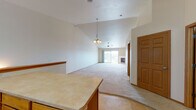 This single-floor home offers a thoughtfully designed open-concept layout that seamlessly connects the main living areas. The expansive living room is a standout feature, boasting soaring vaulted ceilings, a ceiling fan, and a classic chandelier that add character and a sense of airiness. A fireplace serves as a central focal point, while a sliding glass door opens to an outdoor balcony, flooding the space with natural light and providing pleasant exterior views. Plush wall-to-wall carpeting runs throughout the living and bedroom areas, lending warmth underfoot.

The kitchen is well-appointed with warm oak cabinetry, light countertops, tile flooring, and a full suite of white appliances including a range, microwave, dishwasher, and refrigerator. A central island with additional cabinetry provides extra prep and storage space, making this an efficient and functional cooking area.

The bedrooms are comfortably sized with carpeted floors, neutral walls, and ample closet space. The bathrooms are finished with tile flooring and oak vanity cabinetry. One bathroom includes a dual-sink vanity and a stacked washer and dryer unit, offering the added convenience of in-unit laundry. Overall, the home presents a clean, neutral palette and practical design throughout.