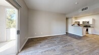 Located at 7413 W Russell Rd in Las Vegas, NV, this two-bedroom, three-bathroom residence offers a well-designed single-floor layout with a clean, contemporary aesthetic. The open-concept living and dining area is finished with wood-look flooring in a warm gray tone, neutral-painted walls, and a sliding glass door that fills the space with natural light and provides outdoor views. The kitchen is efficiently laid out with white cabinetry, granite-look countertops, a breakfast bar peninsula, and a full suite of stainless steel appliances including a gas range, built-in microwave, dishwasher, and refrigerator. Overhead lighting brightens the workspace, making it both functional and inviting. Both bedrooms feature plush carpeting and windows with exterior views, offering a comfortable and quiet retreat. The primary bedroom is generously sized and connects to a bathroom with a granite-top vanity, wood-look flooring, and an adjacent walk-in closet with built-in shelving and hanging rods. The bathrooms throughout maintain a consistent, clean design with white fixtures and tile surrounds. A dedicated closet adds to the practical storage solutions available in this well-appointed residence.