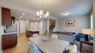 Located in Lee's Summit, Missouri, this two-story home offers a thoughtfully designed layout across two well-organized floors. The main level centers around an open-concept living, dining, and kitchen area, seamlessly connected for everyday living and entertaining. The kitchen is equipped with rich dark wood cabinetry, granite countertops, stainless steel appliances including a range, microwave, refrigerator, and dishwasher, and a central island with a double sink and pendant lighting overhead. Light wood-style flooring extends throughout the main level, complementing the neutral gray walls. The dining area accommodates a full-sized table and is illuminated by an elegant chandelier, with a sliding glass door providing access to the outdoors and bringing in natural light. The living room features large windows that brighten the space. Upstairs, the bedrooms are carpeted and well-sized, each offering ample natural light through double-pane windows. The bedrooms include double-door closets for generous storage. The bathrooms feature tile flooring, wood vanities, and a glass-enclosed shower. A dedicated laundry room with tile flooring and washer/dryer hookups adds practicality to the upper level.