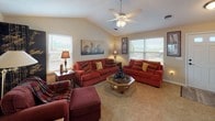 This single-story home offers a well-organized layout across several distinct spaces. The galley-style kitchen is equipped with stainless steel appliances, including a gas range, refrigerator, and dishwasher, complemented by warm wood cabinetry, light granite-style countertops, and light hardwood-style flooring. A window above the sink area allows natural light to brighten the workspace.

The living room is a standout feature, boasting vaulted ceilings and a ceiling fan, with multiple windows on opposing walls that flood the room with natural light and views of the surrounding landscape. Neutral carpet and warm-toned walls contribute to a comfortable ambiance.

A dedicated office space provides a functional area with carpeted flooring and a window offering natural light, suitable for a home workspace. The bedroom is a cozy, well-proportioned room with neutral walls and textured ceilings.

The bathroom includes a single-sink vanity with matching cabinetry, a tub/shower combination, hardwood-style flooring, and access to an open walk-in closet with built-in shelving for organized storage.

Completing the home is an attached single-car garage with an automatic opener, offering additional utility and convenience.