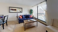 The 68 Harrison Model is a two-bedroom, one-bathroom single-floor unit designed for functional, comfortable living. Light wood flooring runs throughout the space, creating a cohesive and warm aesthetic from room to room.

The living area serves as the heart of the unit, featuring expansive floor-to-ceiling windows that flood the space with natural light and offer open city views. A pass-through window connects the living room to the kitchen, enhancing the open feel between the two spaces.

The kitchen is equipped with rich dark wood cabinetry, white appliances including a refrigerator and range, and light countertops. A peninsula with bar seating provides additional dining and prep space, making it practical for everyday use.

The primary bedroom is generously sized, benefiting from large windows with urban views and ample room for furnishings. The second bedroom also features notable window placement, bringing in natural light and offering additional city views, making it a versatile space suitable for various uses.

The bathroom is finished with light wood-style flooring, a dark wood vanity with an integrated sink, and a shower-tub combination.

Overall, the unit presents a bright, clean, and well-organized layout with a consistent design language throughout.