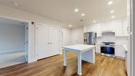 Located at 857A Federal Rd in Brookfield, CT, this well-appointed 2-bedroom, 2-bathroom residence offers a thoughtfully designed single-floor layout with a clean, modern aesthetic throughout. The open-concept kitchen serves as the heart of the home, showcasing crisp white shaker cabinetry extending to the ceiling, stainless steel appliances including a French door refrigerator with ice maker, a gas range, built-in microwave, and dishwasher. A central island with a white quartz countertop provides additional prep and dining space, all illuminated by recessed lighting above warm hardwood flooring. The living room is bright and airy, benefiting from large windows and a glass door that fill the space with natural light and offer views of the surrounding landscape. The generously sized primary bedroom features plush wall-to-wall carpeting, a walk-in closet with built-in wire shelving, and direct access to its own full bathroom. The second bedroom is equally comfortable with soft carpeting and convenient access to the main living area. Both bathrooms are finished with classic mosaic tile flooring, a tub-shower combination, and vanity storage. Two hallways connect the spaces seamlessly, completing this clean and functional home.