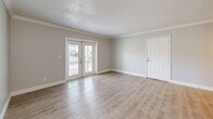 Located in Winter Garden, FL, this 2-bedroom, 1-bathroom single-story home offers a clean, modern aesthetic throughout. Light wood-tone luxury vinyl flooring flows seamlessly across all living areas, complemented by neutral gray walls, crisp white trim, and textured ceilings with crown molding throughout.

The open living and dining area is bright and inviting, featuring a ceiling fan and French doors that open to a private patio, flooding the space with natural light and providing easy outdoor access. The well-appointed kitchen is a standout feature, showcasing warm wood-grain cabinetry with gold-toned hardware, quartz countertops, a deep stainless steel undermount sink, a decorative tile backsplash, and stainless steel appliances including a range, microwave, and dishwasher.

Both bedrooms are comfortably sized with large windows dressed in white blinds that allow ample natural light. Each room includes closet storage, and the primary bedroom offers generous proportions. The bathroom is neatly finished with a tiled tub-shower surround, a vanity with a light countertop, brushed nickel fixtures, and matching wood-tone flooring. A utility room and hallway complete the efficient, well-organized layout of this move-in-ready home.