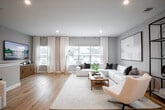 This well-appointed 2-bedroom, 2-bathroom home in East Patchogue, NY offers a thoughtfully designed layout with modern finishes throughout. The open-concept living room is bright and welcoming, featuring light hardwood flooring, recessed lighting, and large windows that invite abundant natural light. The kitchen is a standout space, showcasing crisp white shaker cabinetry with matte black hardware, a white quartz peninsula with seating, subway tile backsplash, stainless steel appliances, and pendant lighting — a perfect blend of form and function. The spacious primary bedroom provides a serene retreat, complete with plush carpeting, a walk-in closet, and a dedicated en-suite bathroom. The second bedroom offers generous natural light through large windows with neighborhood views. Both bathrooms are finished with elegant marble-style tile, matte black fixtures, and white vanities; one features a soaking tub and the other a sleek glass-enclosed walk-in shower. A dedicated laundry room with a full-size washer and dryer adds everyday convenience. Carpeted stairs with a warm wood handrail connect the levels, completing this clean, modern home.