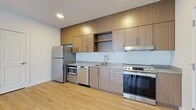 Located at 849 E Magnesium Rd in Spokane, WA, this thoughtfully designed one-bedroom, one-bathroom residence offers a clean, modern aesthetic throughout its efficiently utilized single-floor layout. The open kitchen is a standout feature, showcasing contemporary wood-grain cabinetry extending to the ceiling, stainless steel appliances including a refrigerator, electric range, dishwasher, and built-in microwave, along with light gray countertops and a single-basin sink. Light wood-style flooring runs throughout the main living areas, lending warmth and continuity to the space. The living area is bright and open, with a sliding glass door that leads to a private patio overlooking a landscaped courtyard, allowing natural light to fill the room. The bedroom is finished with plush carpet and features a large sliding window with exterior views, providing a quiet and comfortable retreat. A dedicated closet offers practical storage. The bathroom is finished with a wood-toned vanity, white quartz countertop, a large mirror, and light flooring, creating a clean and functional space. A hallway connects the rooms efficiently, completing this well-appointed, move-in-ready residence.