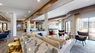 This thoughtfully designed single-floor amenity space blends contemporary style with comfortable functionality across several distinct areas. The entrance welcomes visitors with large-format tile flooring, paneled accent walls, and curated artwork framed by elegant gold sconce lighting. A business center nearby features decorative open-brick partitions, wood-paneled walls, and built-in workstations with bar-height seating — creating a focused yet visually striking workspace.

The expansive main lounge is anchored by soaring ceilings with bold exposed wood beams, recessed lighting, and textured columns. A generous seating arrangement with a polished stone-top counter, sculptural gold accent stools, and a wall-mounted flat-screen TV defines the social hub of the space. A billiards table and additional game tables extend the entertainment options, while large glass doors flood the area with natural light and offer views to an outdoor area.

A private screening room offers a more intimate retreat, featuring a large projection screen, a built-in wet bar with beverage refrigerators, a velvet sofa, and dramatic textured wall treatments with accent lighting. The café-style dining nook rounds out the space with upholstered banquette seating, round marble-top tables, leather chairs, and shiplap-style wall paneling, providing a relaxed setting for casual gatherings.