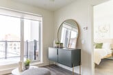 Located at 125 Canon Jackson Dr in Toronto's Mount Dennis neighbourhood, this thoughtfully designed one-bedroom, one-bathroom unit offers a compact yet functional layout across a single floor. The interior is finished in a clean, modern palette of white walls, light wood-tone flooring, and crisp trim throughout.

The living room is a bright, inviting space anchored by large sliding glass doors that open onto a private balcony, flooding the room with natural light and providing open views of the surrounding Toronto streetscape. The kitchen is efficiently designed with two-tone cabinetry — white upper cabinets and wood-finish lower drawers — complemented by light quartz countertops, a subway tile backsplash, stainless steel appliances, and a deep single-basin sink.

The bedroom is a serene retreat featuring an oversized window with expansive city views, mirrored sliding closet doors that enhance the sense of space, and a soft, neutral aesthetic. The bathroom is clean and well-appointed, offering a full soaker tub and shower combination with white subway tile surround.

A hallway connects the rooms efficiently, keeping the layout organized and accessible. Throughout the unit, recessed lighting, modern fixtures, and consistent flooring create a cohesive, polished feel well-suited for urban living.