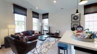This single-floor residence offers a thoughtfully designed layout that balances modern aesthetics with everyday functionality. The open-concept living area welcomes you through a bold, dark-trimmed front door with a transom window, flooding the space with natural light from multiple double-hung windows dressed with woven roman shades. Light wood-look flooring flows throughout the main areas, complementing the neutral walls and dark baseboards for a clean, contemporary contrast.

The kitchen is a standout feature, showcasing a two-tone design with white upper cabinetry and warm wood-grain lower cabinets, paired with quartz countertops and a white subway tile backsplash. Stainless steel appliances, including a gas range and built-in microwave, add a polished finish. A peninsula provides additional prep and seating space. A striking herringbone-patterned feature wall adds a bold architectural accent near the kitchen entry.

The living room offers generous space for entertaining, with recessed lighting and a seamless connection to the kitchen bar area. The two bedrooms are carpeted for comfort—one features a dramatic dark grid-tile accent wall, while the other benefits from sliding glass door access and ample natural light. The bathroom is clean and functional, featuring a floating wood-tone vanity, a tiled tub-shower combination, and light wood-look flooring.