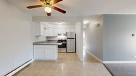 Located at 650 S York Rd in Bensenville, Illinois, this single-floor unit offers a practical and straightforward layout designed for comfortable everyday living. The kitchen is a functional centerpiece, featuring white cabinetry, speckled laminate countertops with a peninsula overhang, a stainless steel refrigerator, and a stainless steel range. Light tile flooring runs throughout the kitchen area, and a ceiling fan overhead adds to the practicality of the space.

The living area is generously sized, finished with neutral carpet and painted in soft, muted tones. A sliding glass door with vertical blinds fills the room with natural light and provides direct access to an outdoor space, while a wall-mounted air conditioning unit and baseboard heating ensure year-round comfort.

The bedrooms are carpeted and bright, each featuring windows with views of surrounding greenery and baseboard heating. The bathroom includes a full tub-shower combination with white tile surround, a yellow tub, and a white vanity. Throughout the unit, clean white trim and neutral wall tones create a cohesive, understated aesthetic.