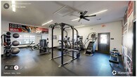 Located at 2190 Ocean Reef Pl in Raleigh, NC, this fitness center spans a single floor and is divided into two exercise rooms, together offering a comprehensive workout environment. The space features durable rubber flooring throughout, providing both safety and comfort during training sessions.

The primary exercise room is appointed with a variety of strength and cardio equipment, including a power rack with weight plates, treadmills, ellipticals, a stair climber, and cable machines. A striking sports-themed mural covers one wall, incorporating bold red and black imagery that energizes the atmosphere. Linear LED lighting runs along the ceiling, complemented by ceiling fans that help maintain air circulation. Large mirrors along the walls enhance the sense of openness and allow users to monitor their form.

The secondary exercise room continues the fitness theme with additional cardio machines, including an Echelon bike and treadmills, along with a full free weight station featuring a dumbbell rack, kettlebells, and a flat bench. Natural light filters in through multiple windows, brightening the space. Glass doors connect the two rooms and provide a view into an adjacent recreation area. The overall aesthetic is clean, modern, and motivational, making this fitness center a fully functional resource for residents.