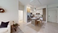 This well-appointed 2-bedroom, 2-bathroom residence at 4970 SW 124th Ave offers thoughtfully designed single-floor living with a clean, contemporary aesthetic. The open-concept kitchen is a standout feature, showcasing two-tone cabinetry with high-gloss white upper cabinets and warm wood-finish lower cabinets, light quartz countertops, a white subway tile backsplash, and stainless steel appliances. A central island with bar seating serves as both a functional workspace and a casual dining spot, while pendant lighting adds a polished finishing touch. Large-format tile flooring flows seamlessly through the kitchen and main living areas, enhancing the sense of openness. The living room is bathed in natural light through expansive sliding glass doors, offering outdoor views and easy access to the exterior. A dedicated dining area features a built-in shelving nook, providing both storage and display space. Both bedrooms are comfortably sized, featuring roller shades, soft neutral tones, and a calm, restful atmosphere. The second bedroom includes an arched ceiling detail that adds architectural character. The bathrooms are finished in light, neutral tones with wood-accented vanities and tub-shower combinations. Throughout the residence, the consistent use of warm wood tones, crisp whites, and soft neutrals creates a cohesive and inviting modern living environment.