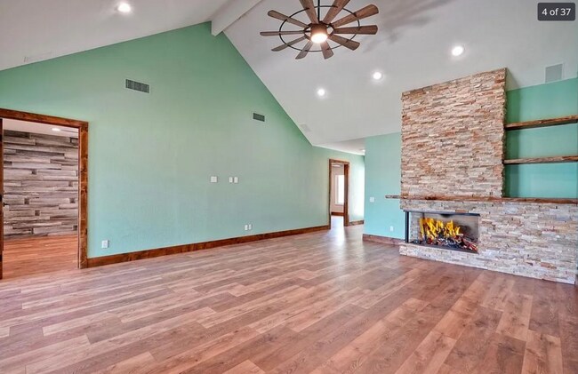 Salón con chimenea de piedra natural, repisa y estanterías de madera de nogal. - 14787 Caminito Orense Oeste