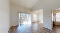 Located at 8404 N Loop Dr in El Paso, Texas, this single-floor unit offers a well-organized layout with thoughtful design details throughout. The open living and dining area is a standout feature, showcasing soaring vaulted ceilings that lend an airy, spacious feel to the space. Wood-look plank flooring runs consistently throughout the unit, adding warmth and cohesion. A full-width sliding glass door floods the living area with natural light and provides direct access to an outdoor patio, where views of surrounding greenery can be enjoyed.

The kitchen is equipped with dark espresso cabinetry accented by gold hardware, white countertops, a stainless steel electric range with an overhead ventilation hood, and a full-size refrigerator — offering ample storage and workspace for everyday cooking.

A hallway with textured walls and wall sconce lighting connects the main living area to the private quarters. The bedroom features vaulted ceilings, wood-look flooring, a ceiling fan, and access to a dedicated walk-in closet, providing generous storage. The full bathroom includes a white-tiled shower and tub combination, a vanity with a sink, and wood-look flooring that ties in seamlessly with the rest of the unit.