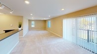 This single-floor residence features three bedrooms and two bathrooms within a thoughtfully arranged floor plan. The kitchen serves as a central highlight, equipped with rich wood cabinetry, dark granite-style countertops, stainless steel appliances including a refrigerator, electric range, and built-in microwave, and a double stainless steel sink. Track lighting illuminates the space, and a peninsula counter separates the kitchen from the adjoining living area, which features neutral carpet flooring. The bedrooms are carpeted and finished with warm beige walls, each featuring windows with vertical blinds that allow natural light. One bedroom includes access to a spacious walk-in closet outfitted with adjustable white shelving and hardwood-style flooring, providing ample organization options. The two bathrooms are finished with tile flooring, white vanities, and clean, neutral color palettes. The primary bathroom includes a soaking tub, while the secondary bathroom features a shower with a decorative curtain. Throughout, consistent warm tones and clean finishes create a cohesive, move-in-ready atmosphere.