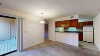 This single-story residence offers a practical and comfortable layout with clearly defined living spaces throughout. The living room serves as the central gathering area, featuring wall-to-wall carpet, a tile-surround fireplace with a wood mantel, and a sliding glass door that opens to a private balcony, allowing natural light to fill the space. A pendant light fixture hangs overhead, complementing the textured ceiling found throughout the unit.

The kitchen is efficiently designed with warm-toned wooden cabinetry, dark granite-style countertops, and tile flooring. White appliances—including a refrigerator, electric range, and dishwasher—are included. A pass-through counter connects the kitchen to the adjacent dining area, enhancing the open feel between these spaces. A utility panel is conveniently accessible within the kitchen corridor.

The bedrooms are carpeted and offer neutral walls with ample room for furnishings. Each room includes standard closet access and connects to the broader hallway layout. The bathroom features a full soaking tub with a tiled surround, a grab bar, and tile flooring, offering a clean and functional design. Overall, the space presents a straightforward, functional layout well-suited for everyday living.