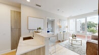 This thoughtfully designed single-floor residence combines contemporary style with functional living. The open-concept layout seamlessly connects the kitchen and living area, creating an inviting and airy atmosphere bathed in natural light from large windows. The kitchen is outfitted with stainless steel appliances, including a slide-in range, built-in microwave, and French door refrigerator, complemented by white upper cabinetry, warm wood-toned lower cabinetry, and crisp quartz countertops. A peninsula with bar seating and an undermount sink adds both utility and a social focal point to the space. Light hardwood flooring flows throughout, enhancing the home's bright, cohesive aesthetic. The living area offers a welcoming retreat with ample space for entertaining. Two well-proportioned bedrooms each feature windows that bring in natural light and views of the surrounding area. The primary bedroom is accompanied by a spacious walk-in closet with built-in wire shelving and a private en-suite bathroom featuring a glass-enclosed shower, wood-toned vanity, and large-format tile flooring. A second full bathroom mirrors the refined design with a similarly styled vanity and neutral tile finishes. A hallway lined with louvered storage doors and framed artwork completes the home's polished, contemporary character.