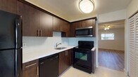 Located at 1240 NW 13th St in Boca Raton, Florida, this single-story unit offers a thoughtfully updated interior with a cohesive, modern aesthetic. The kitchen serves as a standout feature, showcasing rich dark-brown cabinetry with sleek bar-pull hardware, crisp white countertops, and a light glass-tile mosaic backsplash. Black appliances — including a refrigerator, electric range, built-in microwave, and dishwasher — complement the dark cabinetry for a unified look, while a flush-mount ceiling light provides focused illumination.

The living areas and bedrooms are finished with light wood-look flooring that runs consistently throughout, contributing to a bright and cohesive feel. Textured ceilings and ceiling fans with integrated lighting are found across the main rooms, enhancing both comfort and airflow. Bedrooms are generously proportioned, with large windows framing views of the surrounding Florida tropical landscaping. One room features a sliding glass door opening to a private balcony with palm tree views. A bathroom with a dark vanity and well-lit mirror is conveniently accessible from the bedroom area. Clean white walls and abundant natural light give the entire space a fresh, move-in-ready atmosphere.