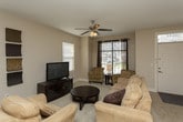 This two-story home offers a functional and comfortable layout with well-defined living spaces across both levels. The main floor opens into a bright living room with neutral carpet, a ceiling fan, and large windows that allow ample natural light. Adjacent to it, a formal dining area connects seamlessly to the kitchen through a convenient pass-through window, enhancing the open feel of the space. The kitchen is a standout feature, equipped with rich dark wood cabinetry, granite countertops, stainless steel appliances including a range and built-in microwave, a double sink, dishwasher, and a central island with bar seating — all set on light tile flooring. A secondary living area near the entry staircase provides additional flexible space. Upstairs, the primary bedroom is generously sized with a tray ceiling, ceiling fan, plush carpet, and multiple windows. It connects to a spacious ensuite bathroom featuring dual vanities, a walk-in shower, a separate soaking tub, and a private water closet. A second bedroom with its own ensuite access and tray ceiling detail adds further comfort. A full guest bathroom with vanity and shower-tub combo rounds out the upper level, making this home practical for a variety of living arrangements.