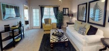 This thoughtfully designed two-bedroom, two-bathroom residence spans a single floor and delivers a comfortable, functional layout ideal for everyday living. The carpeted living room serves as the heart of the home, featuring a ceiling fan, an arched entryway, and French doors that open onto a private balcony, allowing natural light to fill the space. Adjacent to the living area, a dedicated dining nook with pendant lighting and chair-rail molding provides an intimate setting for meals. The galley-style kitchen is well-appointed with rich wood cabinetry, dark granite-style countertops, hardwood flooring, and black appliances, including a refrigerator and dishwasher. A hallway off the kitchen leads directly to an in-unit laundry area. The primary bedroom is generously sized with plush carpet, a ceiling fan, and a large window. The second bedroom offers a cozy retreat with its own window and ample natural light. Both bathrooms feature wood cabinetry with neutral countertops, hardwood flooring, and full soaking tub-shower combinations. Throughout the residence, neutral wall tones and consistent finishes create a cohesive and welcoming ambiance.
