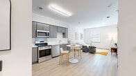 This well-designed one-bedroom, one-bathroom residence in Richmond, Virginia offers a thoughtfully planned open-concept layout that maximizes every inch of its single-floor footprint. The combined kitchen, dining, and living area serves as the heart of the home, featuring light wood-tone flooring that flows seamlessly throughout. The contemporary kitchen is outfitted with sleek gray cabinetry, white countertops, a full suite of stainless steel appliances including a refrigerator, range, microwave, and dishwasher, and a compact dining area with a round table and bar-style seating. The living area benefits from natural light through a window overlooking the surrounding neighborhood. The private bedroom is a comfortable retreat with clean white walls, light flooring, and direct access to a closet. The full bathroom features tile flooring and a shower-tub combination. Additional highlights include three closets for generous storage, an in-unit laundry area, and louvered closet doors that add a classic touch. The overall aesthetic is clean, modern, and move-in ready, with a bright, neutral palette that offers a versatile canvas for personalization.