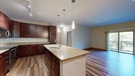 Located at 1505 Wisconsin Ave in Grafton, WI, this single-floor, 2-bedroom, 2-bathroom residence offers a thoughtfully designed layout with modern finishes throughout. The open-concept kitchen and living area serves as the heart of the home, anchored by a large center island with granite countertops and an undermount sink, illuminated by stylish pendant lighting. Rich dark-wood cabinetry, stainless steel appliances — including a refrigerator, range, and microwave — and track lighting complete the kitchen. Wood-style flooring flows throughout the main living areas, adding warmth and continuity. The spacious living room opens directly to a private balcony through a sliding glass door, offering pleasant views of mature trees. A stacked in-unit washer and dryer provides added convenience. The primary bedroom is generously sized, with direct access to a full bathroom featuring a walk-in shower with sliding glass doors, a wood-vanity with a light stone countertop, and wood-look flooring. The second bedroom features plush carpeting and a large window framing leafy outdoor views. The second bathroom includes a full tub-shower combination, a matching vanity, and consistent finishes. A dedicated closet completes this well-organized residence.