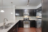 Located at Potomac Heights Place in Woodbridge, VA, this well-appointed one-bedroom, one-bathroom residence is situated on the second floor of an attractive multi-story building with classic brick and neutral-toned exterior. The open-concept living and kitchen area is anchored by rich hardwood flooring and crown molding throughout. The kitchen is a standout feature, boasting dark espresso cabinetry, a mosaic tile backsplash, granite countertops, stainless steel appliances, a peninsula with pendant lighting, and a deep double sink — ideal for both everyday cooking and entertaining. The living room extends to a private balcony through a glass-panel door, offering outdoor views and abundant natural light, complemented by a ceiling fan overhead. The spacious primary bedroom features plush wall-to-wall carpeting, a ceiling fan, and windows that invite natural light and garden views. A dedicated closet provides ample storage just off the bedroom. The full bathroom is well-equipped with a soaking tub, a separate glass-enclosed shower, tile flooring, recessed lighting, and a dark-cabinet vanity topped with a granite countertop. A hallway connects the rooms efficiently, completing this thoughtfully designed and move-in-ready residence.