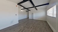 Located at 4115 Palmwood Dr in Los Angeles, CA 90008, this 770-square-foot single-story home offers 2 bedrooms and 1 bathroom across a well-organized floor plan. A defining architectural feature throughout the home is the exposed dark wood beam ceiling, which adds character and visual depth to the bright, white-walled interiors. Hardwood-style flooring flows consistently throughout all rooms, creating a cohesive and clean aesthetic.

The spacious living room is anchored by a grid of exposed ceiling beams and includes a ceiling fan, large windows for natural light, and open sightlines toward the kitchen. The kitchen features white cabinetry, dark countertops, a stainless steel refrigerator, a gas range, a double sink, and windows on multiple walls that fill the space with natural light.

The primary bedroom measures 120 square feet and includes mirrored sliding closet doors and corner windows fitted with blinds. The second bedroom is bright and airy, with wide windows offering neighborhood views. The bathroom is finished in white and includes a vanity with cabinetry and a bathtub. Two hallways connect the rooms efficiently throughout the home. The overall ambiance is clean, minimal, and move-in ready.