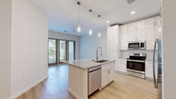 Located at 5701 Summerall Vista Circle in Riverview, FL, this well-appointed one-bedroom, one-bathroom residence offers a thoughtfully designed open-concept layout with modern finishes throughout. Light wood-tone flooring runs seamlessly across the entire space, complementing the bright, neutral color palette that enhances the sense of openness.

The kitchen is a standout feature, showcasing floor-to-ceiling white shaker cabinetry, a classic white subway tile backsplash, and granite countertops. A central island with an undermount sink and pendant lighting above serves as both a functional workspace and a natural gathering point. Stainless steel appliances, including a refrigerator with ice maker, range, microwave, and dishwasher, complete the space.

The kitchen flows directly into the living area, which is bathed in natural light from large sliding glass doors that open to a private balcony, offering outdoor views of the surrounding greenery. A ceiling fan adds comfort to the living space.

The bedroom is generously sized, featuring windows that bring in natural light and direct access to a walk-in closet equipped with wire shelving systems. The bathroom features a granite-topped vanity with white cabinetry, a glass-enclosed walk-in shower with tile surround, and neutral tile flooring, creating a clean and contemporary feel throughout.