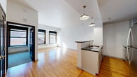 Located in Duluth, Minnesota, this 1-bedroom, 1-bathroom unit offers a well-designed, single-floor layout that makes efficient use of its space. The open-concept living and kitchen area is anchored by warm hardwood flooring that stretches throughout, complemented by crisp white walls and abundant natural light streaming through large, dark-framed windows.

The kitchen features a peninsula with dark countertops and a built-in sink, light gray shaker-style cabinetry reaching toward the ceiling, a subway tile backsplash, and a full suite of stainless steel appliances including a refrigerator, range, and microwave. An in-unit washer is conveniently tucked beside the kitchen. Pendant lighting above the peninsula adds both function and style to the space.

The living area is open and airy, with windows that invite natural light and views of the surrounding Duluth streetscape. The bedroom is carpeted for comfort and includes a window with an exterior view, offering a quiet retreat. A dedicated closet provides additional storage.

The bathroom is finished with neutral tile flooring, a soaking tub with tiled surround, a gray vanity with white countertop, brushed nickel fixtures, and a large mirror — all contributing to a clean, contemporary aesthetic throughout the home.