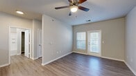 Located at 3340 NE Akin Blvd in Lee's Summit, MO, this well-designed one-bedroom, one-bathroom residence offers a thoughtful single-floor layout with clean, contemporary finishes throughout. The open-concept living room and kitchen area anchors the home, featuring durable wood-look luxury vinyl plank flooring, neutral gray walls, and a ceiling fan with light fixture. Natural light flows in through a large window and glass-panel door that provide outdoor views, giving the living space an airy, welcoming feel. The kitchen is appointed with crisp white cabinetry, stainless steel appliances including a refrigerator, range, and over-the-range microwave, and a peninsula with a light-colored countertop that doubles as a breakfast bar. A pendant chandelier adds a polished touch above the dining area. The bedroom offers plush carpeting, a ceiling fan, a closet with a built-in rod, and a window overlooking the exterior. The full bathroom includes a tub-shower combo with tile surround, a white vanity, and coordinating fixtures. A dedicated in-unit laundry room with washer and dryer hookups adds everyday convenience. The space presents a modern, move-in-ready aesthetic throughout.