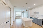 Located at 6735 Standifer Gap Rd in Chattanooga, TN, this thoughtfully designed 2-bedroom, 2-bathroom residence offers a clean, modern aesthetic across a single floor. The open-concept kitchen and living area serves as the heart of the home, anchored by a large center island with a white quartz countertop and pendant lighting in brushed brass. The kitchen features two-tone cabinetry — white upper cabinets paired with slate-blue lowers — complemented by a classic subway tile backsplash and stainless steel appliances, including a French door refrigerator. Light hardwood flooring flows throughout the main living areas, enhancing the bright, airy atmosphere. The living area benefits from generous natural light through large windows and direct access to a private balcony with outdoor views. Both bedrooms are carpeted and well-sized, each offering large windows that draw in natural light. The primary bedroom includes its own dedicated bathroom with a dual-sink vanity, white quartz countertops, gray cabinetry, and a glass-enclosed marble-surround shower. The second bathroom mirrors the same refined finishes with a single vanity and shower. Two closets provide ample storage throughout the unit.