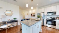 This single-floor, 2-bedroom, 2-bathroom residence in Lebanon, Indiana offers a thoughtfully designed open-concept layout with consistent wood-look flooring and a bright, neutral color palette throughout. The kitchen is a standout feature, equipped with white shaker cabinetry, granite countertops, stainless steel appliances, a subway tile backsplash, and a central island with pendant lighting and bar seating — seamlessly connecting to the living and dining areas. The living room is bright and inviting, benefiting from multiple windows that allow natural light to fill the space, complemented by a ceiling fan and views of the surrounding neighborhood. The primary bedroom offers a comfortable, well-lit retreat with a window, wood-look flooring, and direct access to a private en-suite bathroom featuring white cabinetry, granite countertops, and a walk-in shower. The second bedroom is equally well-sized, also with a window and wood-look flooring. The second bathroom mirrors the home's consistent design aesthetic with white cabinetry and granite countertops. Two closets, a hallway, and a dedicated entrance complete the functional floor plan, making this a practical and attractive residence in Lebanon, IN.