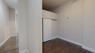 Located at 145 Granby St in downtown Norfolk, VA, this one-bedroom, one-bathroom unit offers a well-planned single-floor layout that maximizes every square foot. Rich, dark hardwood flooring runs continuously throughout the space, creating a warm and cohesive aesthetic.

The open-concept kitchen and living area serves as the heart of the unit. The kitchen is outfitted with stainless steel appliances — including a full-size refrigerator, electric range, dishwasher, and microwave — complemented by dark espresso cabinetry with glass-front upper cabinets and a sleek wall-mounted range hood. Soaring ceilings in this area add a dramatic sense of vertical space.

A hallway connects the main living area to the private bedroom, which features a large window that draws in natural light and offers views of the street below. The bedroom includes a dedicated closet with a modern sliding panel door. In-unit laundry hookups add everyday convenience.

The bathroom is finished with large-format, neutral-toned tile in the tub/shower surround, a white soaking tub, and a dark wood vanity topped with a light stone countertop. Clean white walls throughout the unit provide a neutral, versatile backdrop. The unit also includes a utility panel accessible from the hallway.