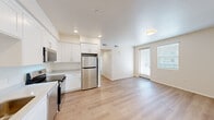 Located at 1385 W College Ave in Santa Rosa, California, this three-bedroom, two-bathroom residence offers a clean, modern design across two floors. The open-concept kitchen and living area serves as the heart of the home, featuring crisp white shaker cabinets, light countertops, and a full suite of stainless steel appliances including a refrigerator, range, over-the-range microwave, and dishwasher. Recessed lighting illuminates the kitchen, while large windows and a glass door in the living area invite abundant natural light and provide easy access to the outdoors. Light wood-style flooring flows seamlessly throughout the entire unit, lending a cohesive and contemporary feel to every room. The three bedrooms are bright and neutral, each finished with the same warm flooring and fitted with window blinds for privacy and light control. The primary bedroom offers a comfortable footprint well-suited for a full bedroom suite. Both bathrooms are finished consistently with white vanity cabinetry, neutral countertops, large mirrors, and tub-shower combinations, maintaining the clean and functional aesthetic found throughout the rest of the home. The overall palette of warm whites and light wood tones creates a fresh, move-in-ready atmosphere throughout this Santa Rosa residence.